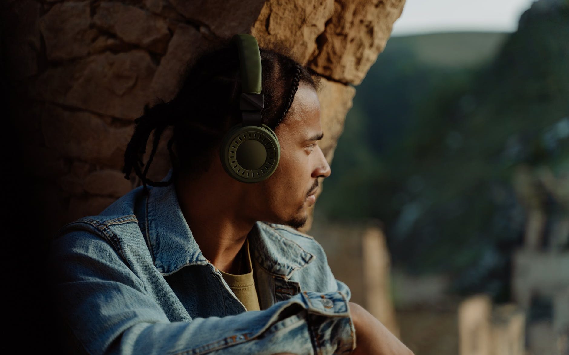 Man with headphones in front of a stone archway